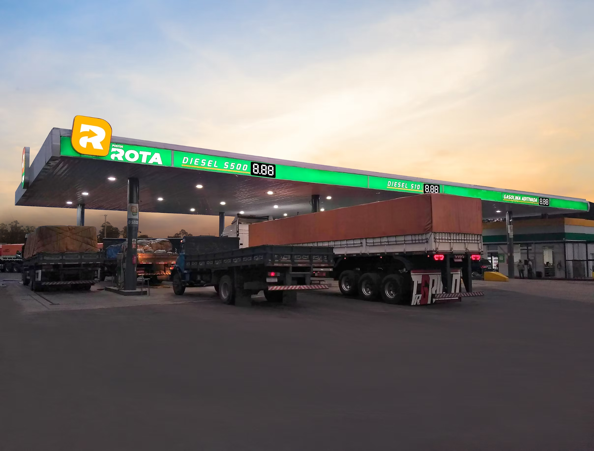 Posto Rota ao pôr do sol com caminhões abastecendo